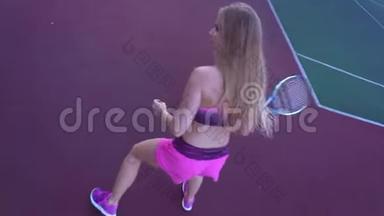 年轻漂亮的女孩打网球。 一个金发的金发，穿着粉红色运动服，专业训练网球。
